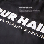 Nahaufnahme einer schwarzen PUR HAIR Friseurschürze mit weißem Logo.