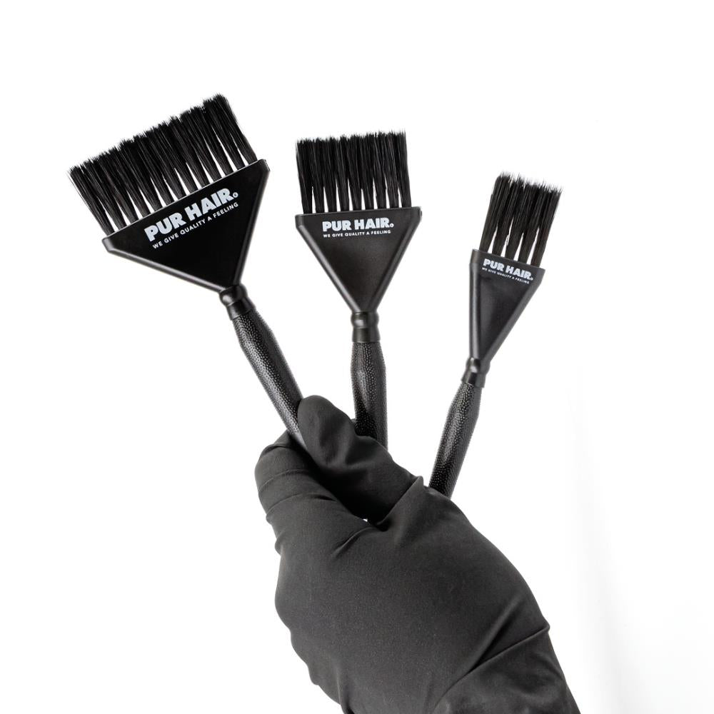 Drei schwarze PUR HAIR Färbepinsel in unterschiedlichen Größen, gehalten von einer Hand