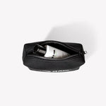 PUR HAIR Travel Bag, in schwarz, mit weißer 100 ml Flasche, auf weißem Hintergrund.
