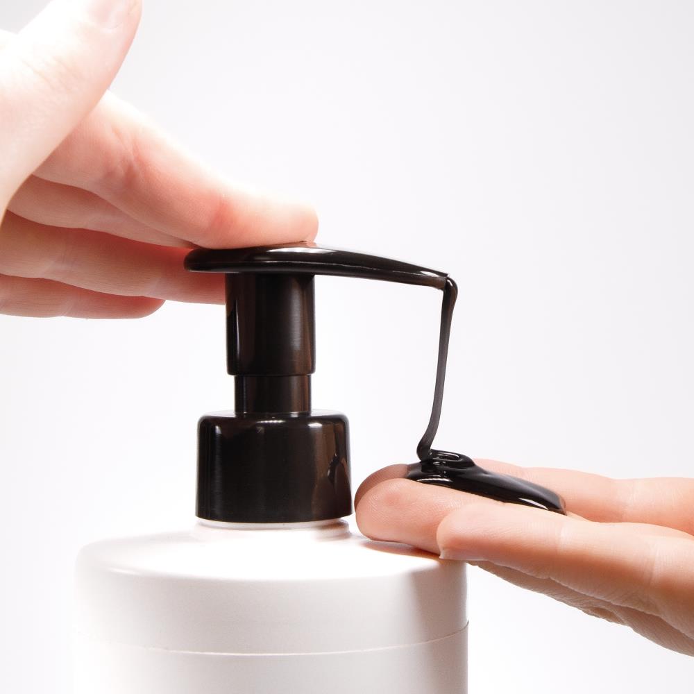Schwarzer Pumpspender einer weißen PUR HAIR Shampoo-Flasche bei der Dosierung des schwarzen Shampoos
