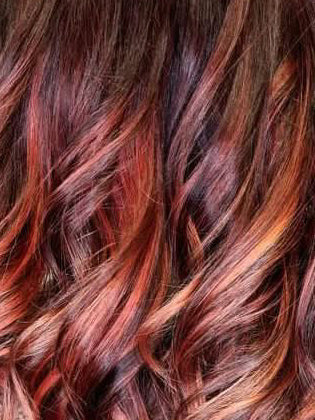 Welliges braunes Haar mit intensiven Rot- und Kupferreflexen als Inspiration für professionelle Haarfarben.