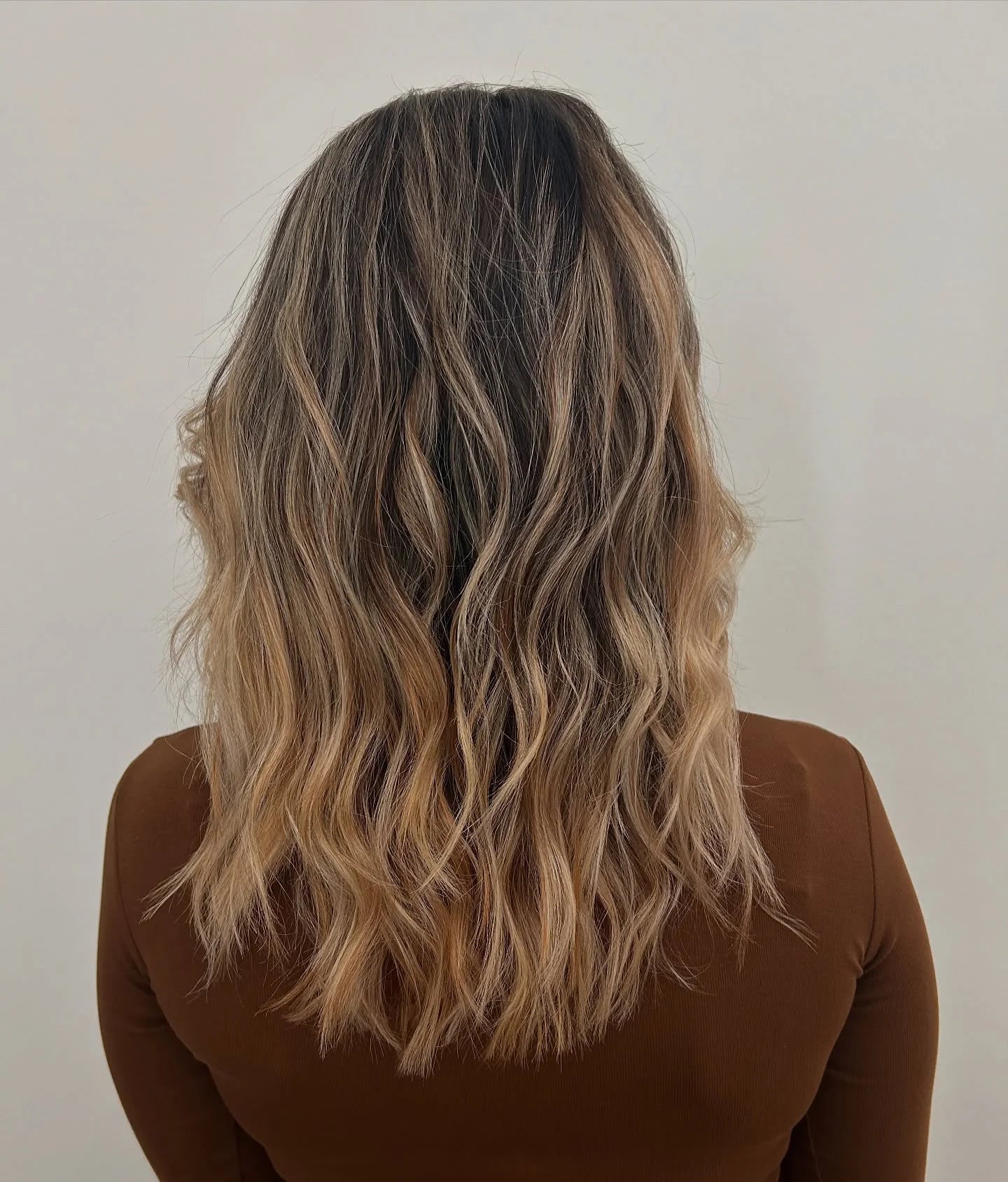 Natürliches Balayage mit dunklem Ansatz und warmen Blondnuancen.