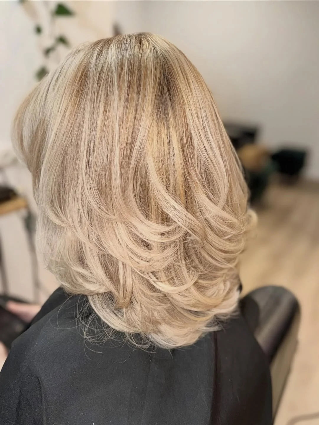 Helles Beige-Blond mit weichen Stufen und voluminösem Styling.