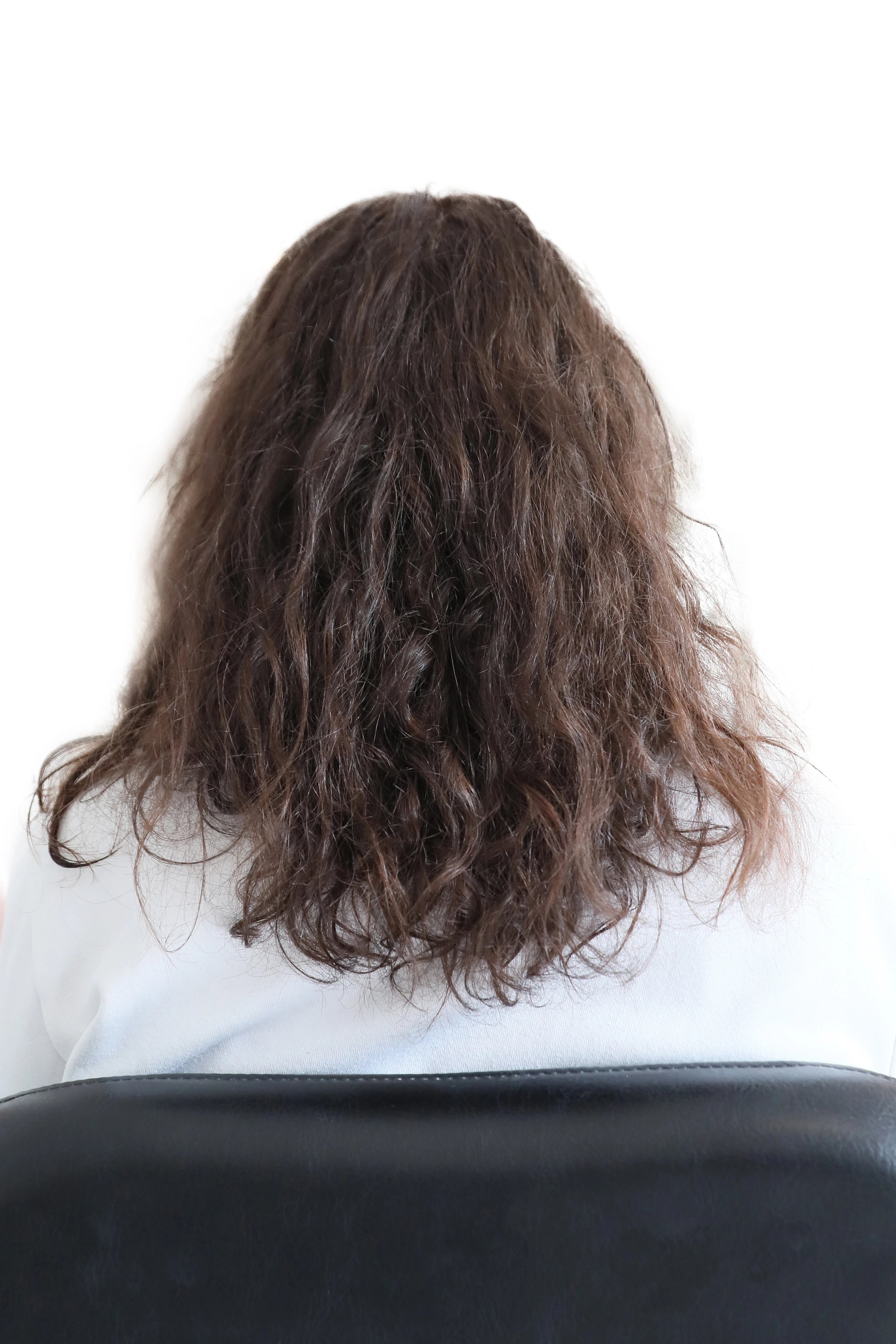 Welliges braunes Haar mit Frizz vor einer professionellen Keratin-Haarglättung im Friseursalon.