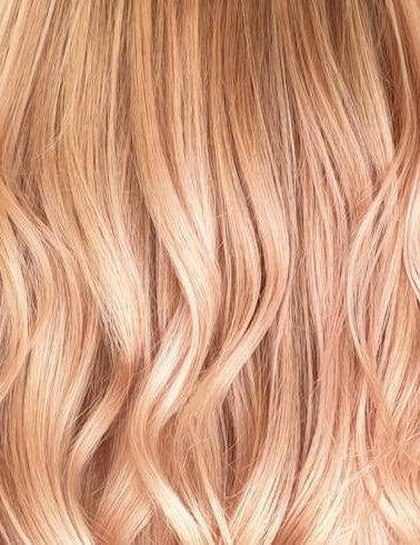 Welliges blondes Haar mit warmem Rosé- und Pfirsichton als Inspiration für professionelle Haarfarben.