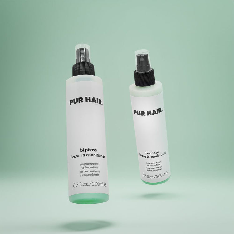 Zwei Flaschen PUR HAIR Bi Phase Leave-in Conditioner, 200 ml, mit Sprühkopf vor grünem Hintergrund.