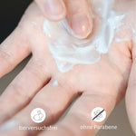 Finger verteilt weiße Haarpflege-Creme in der Hand.