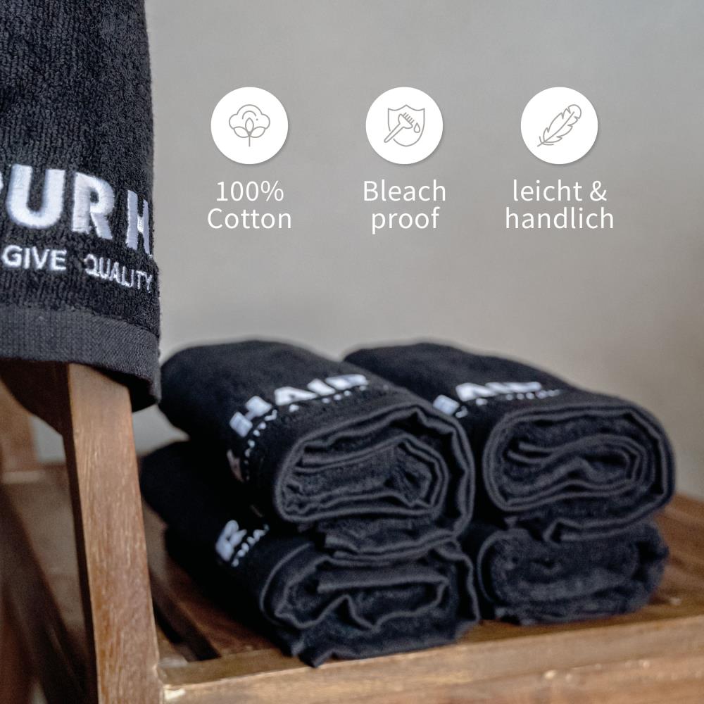 Schwarze PUR HAIR Friseurhandtücher aus 100 % Baumwolle, zusammengerollt auf einer Holzablage