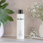 PUR HAIR Organic Moisture Shampoo, 300 ml Flasche in Weiß mit schwarzem Deckel, neben Vase.