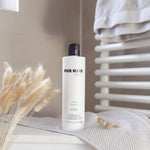 Weiße Flasche PUR HAIR Organic Protein Shampoo, 300 ml, auf grauem Handtuch im Badezimmer platziert.