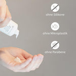 Hand drückt weiße Haarpflegecreme aus PUR HAIR Organic Tube.