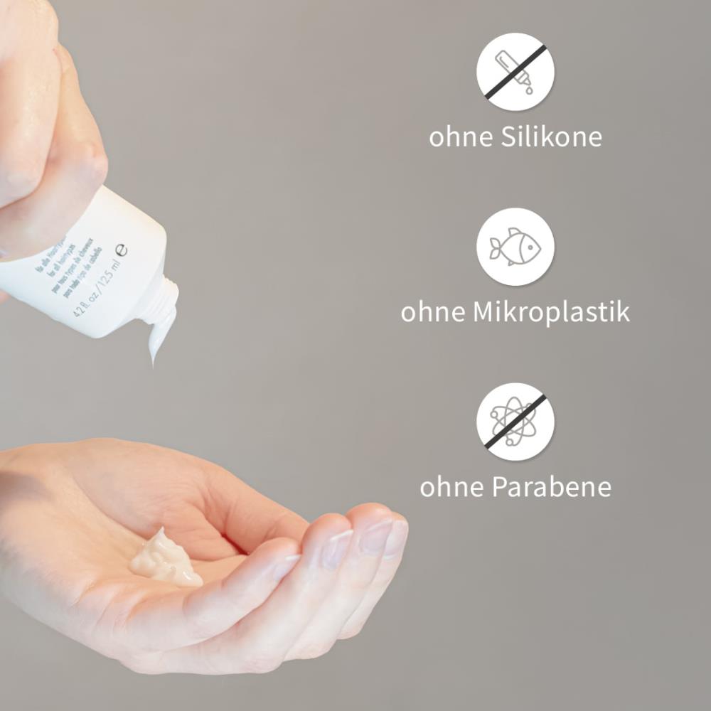 Hand drückt weiße Haarpflegecreme aus PUR HAIR Organic Tube.